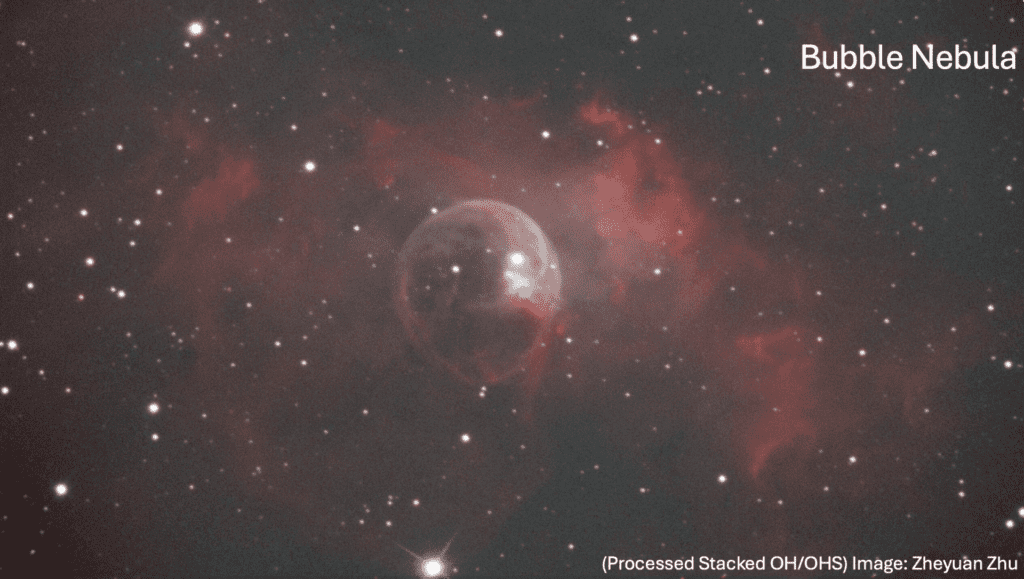 Image of the Bubble Nebula, featuring a spherical, translucent shell surrounded by red-toned clouds in space.